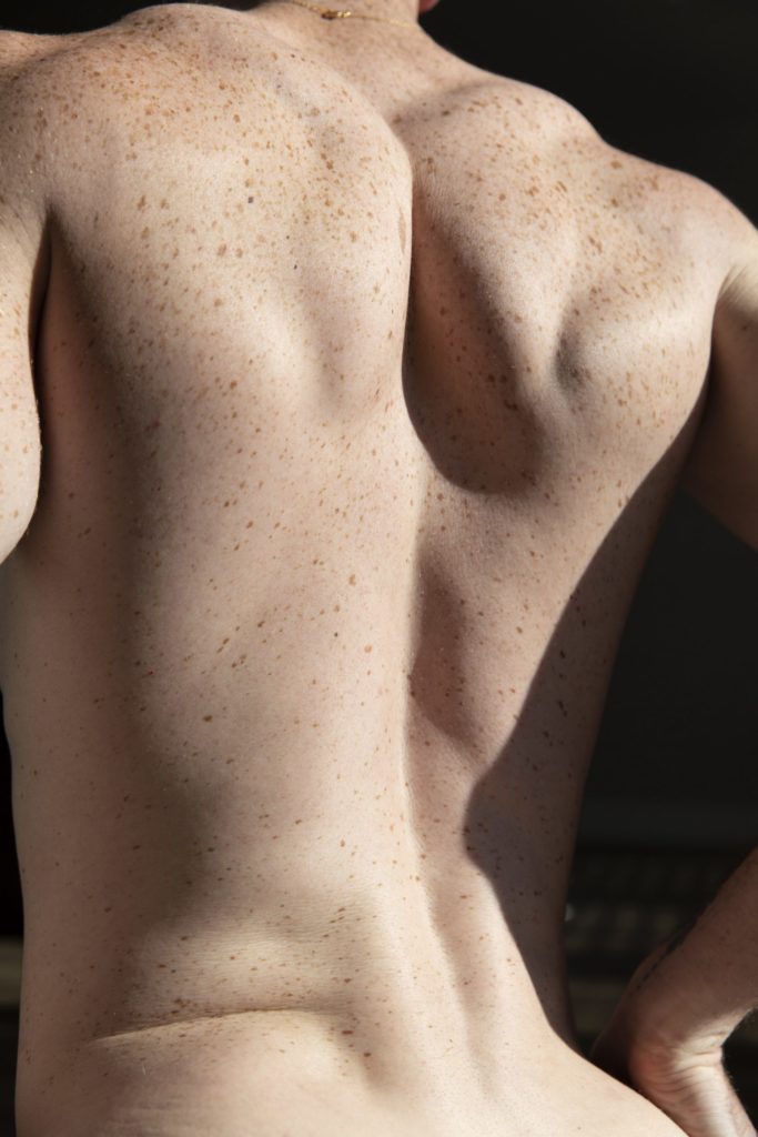A freckled back has been tastefully posed to emphasize the musculature.